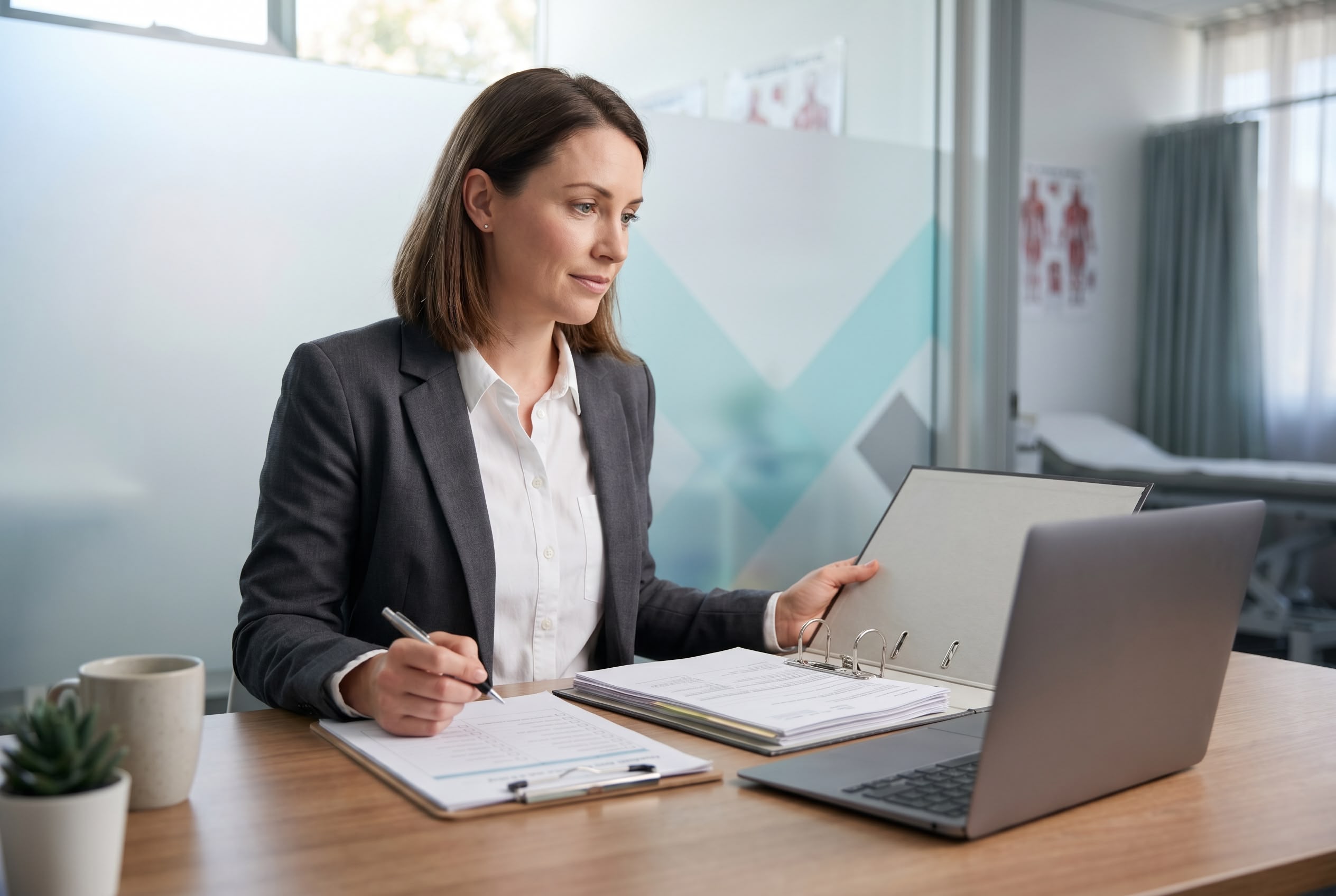 Australian practice manager reviewing RACGP Standards accreditation evidence at her desk in a modern general practice clinic