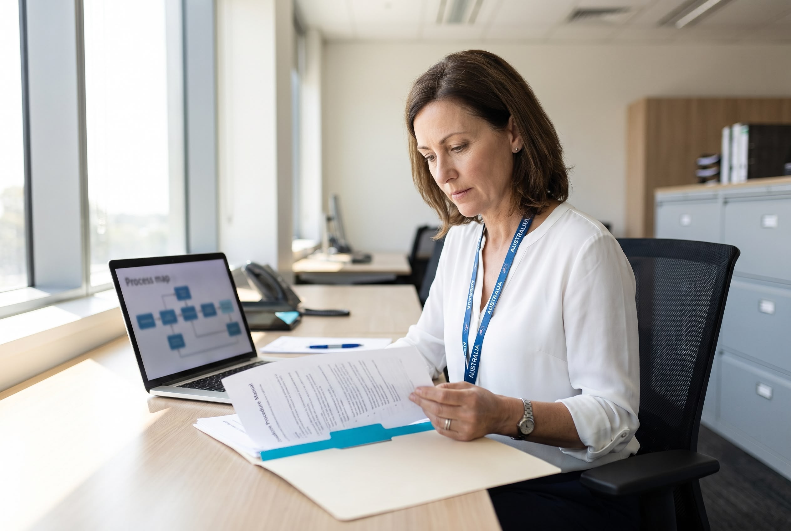 Quality auditing: systems and processes or financials A quality auditor reviewing a procedure manual and a process map in a hospital administration office
